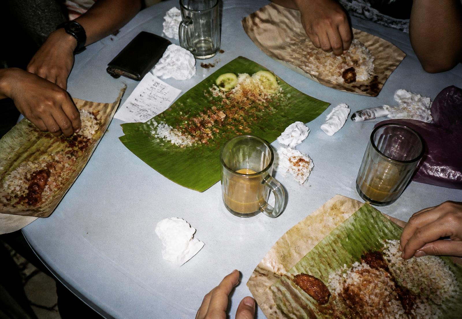 Overhead view of a shared nasi lemak meal on a plastic table