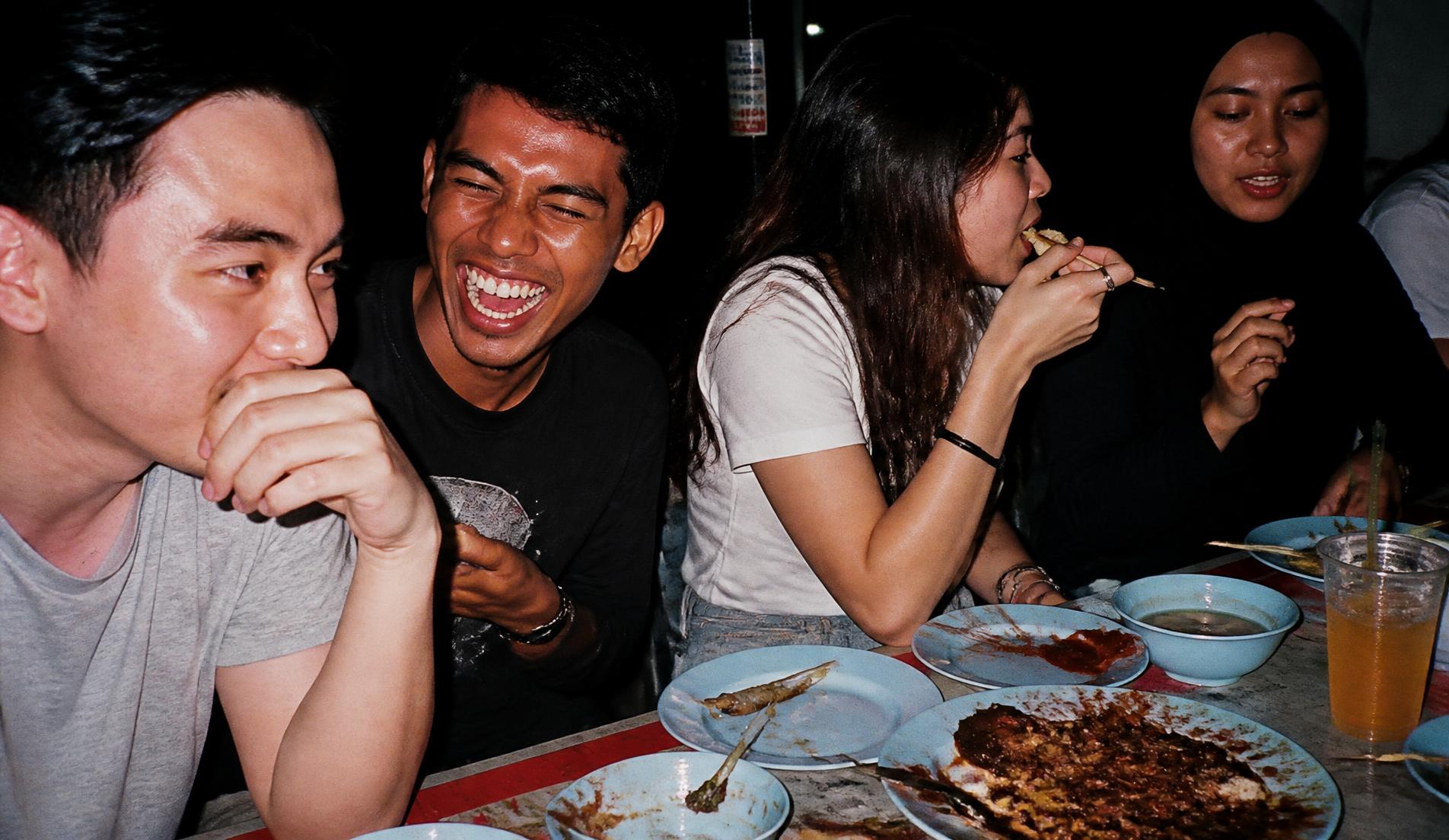 Friends eating together at a late-night roadside stall in Malaysia